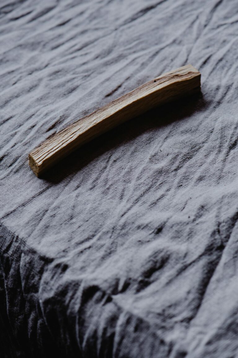 Close-up shot of a Palo Santo stick laid on a textured gray fabric for spiritual rituals.